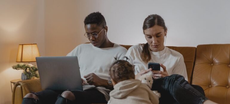 Family on a sofa using a laptop and smartphones at the same time at home