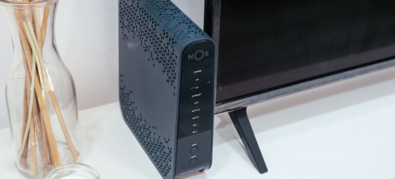 Home WiFi router placed next to a TV on a living room shelf
